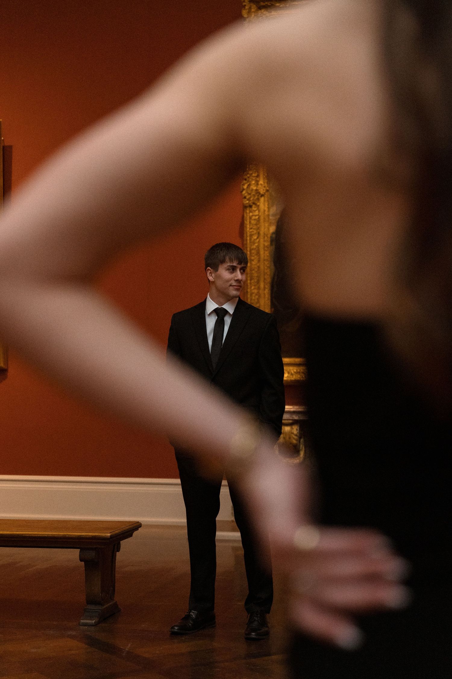Silhouettes move through an elegantly lit museum space with orange walls.