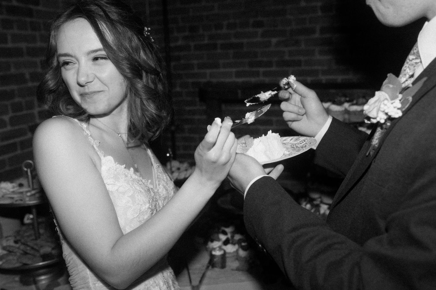 A couple shares an intimate moment during their wedding ceremony against a brick wall backdrop.
