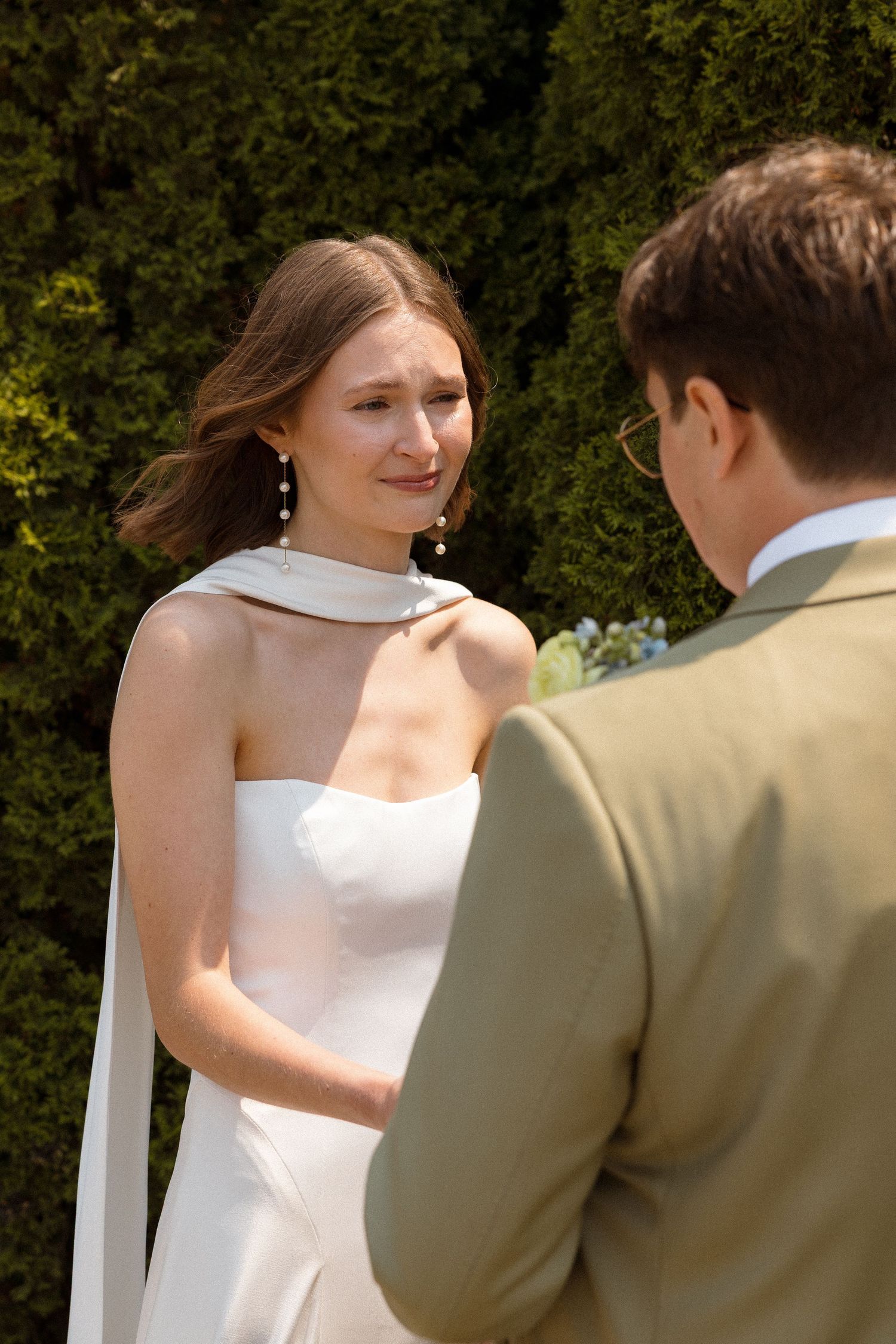 Couple in wedding attire sharing an intimate moment in an outdoor garden setting.
