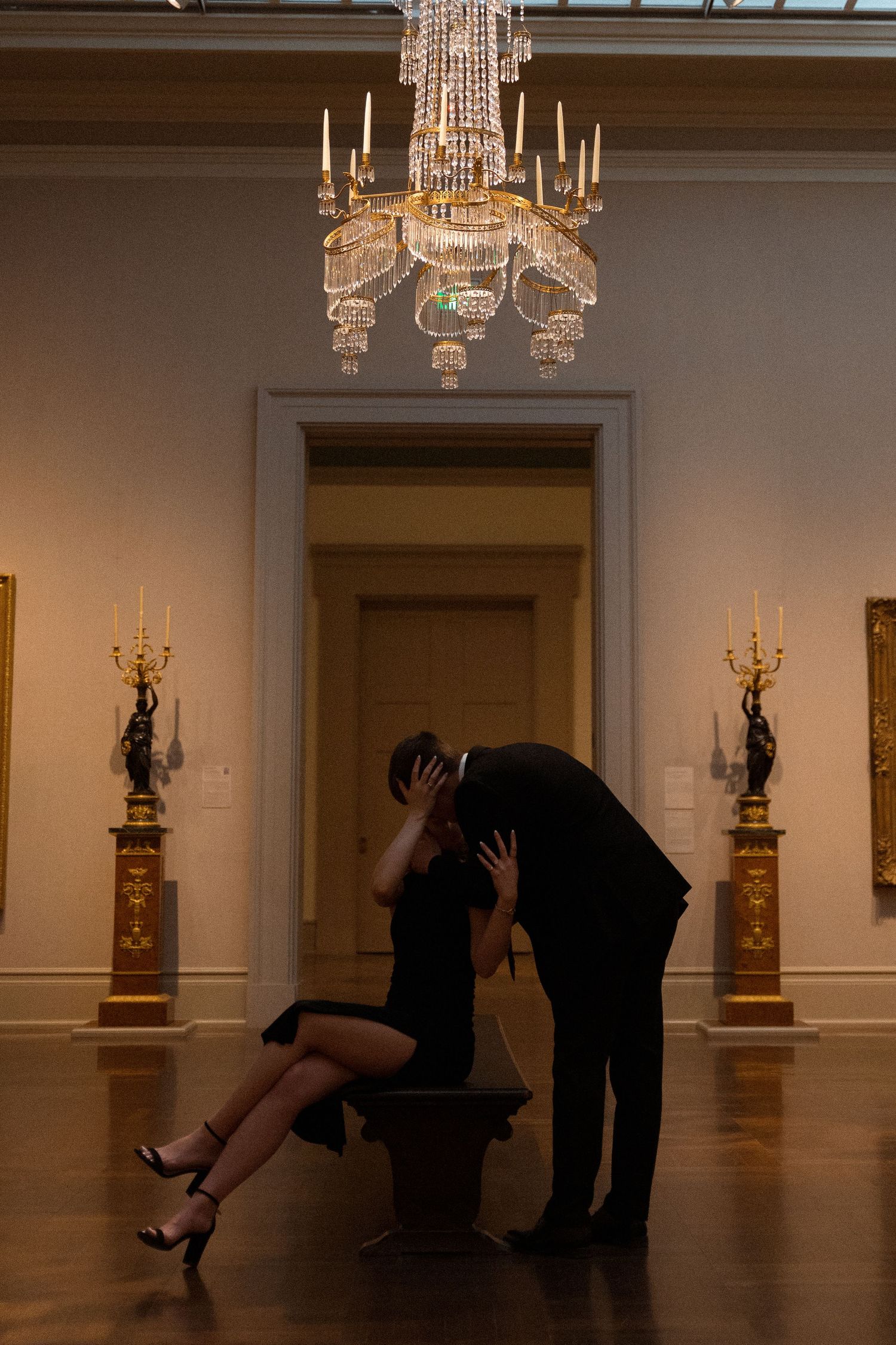 Dynamic dance movements captured in a museum gallery under ornate chandeliers.