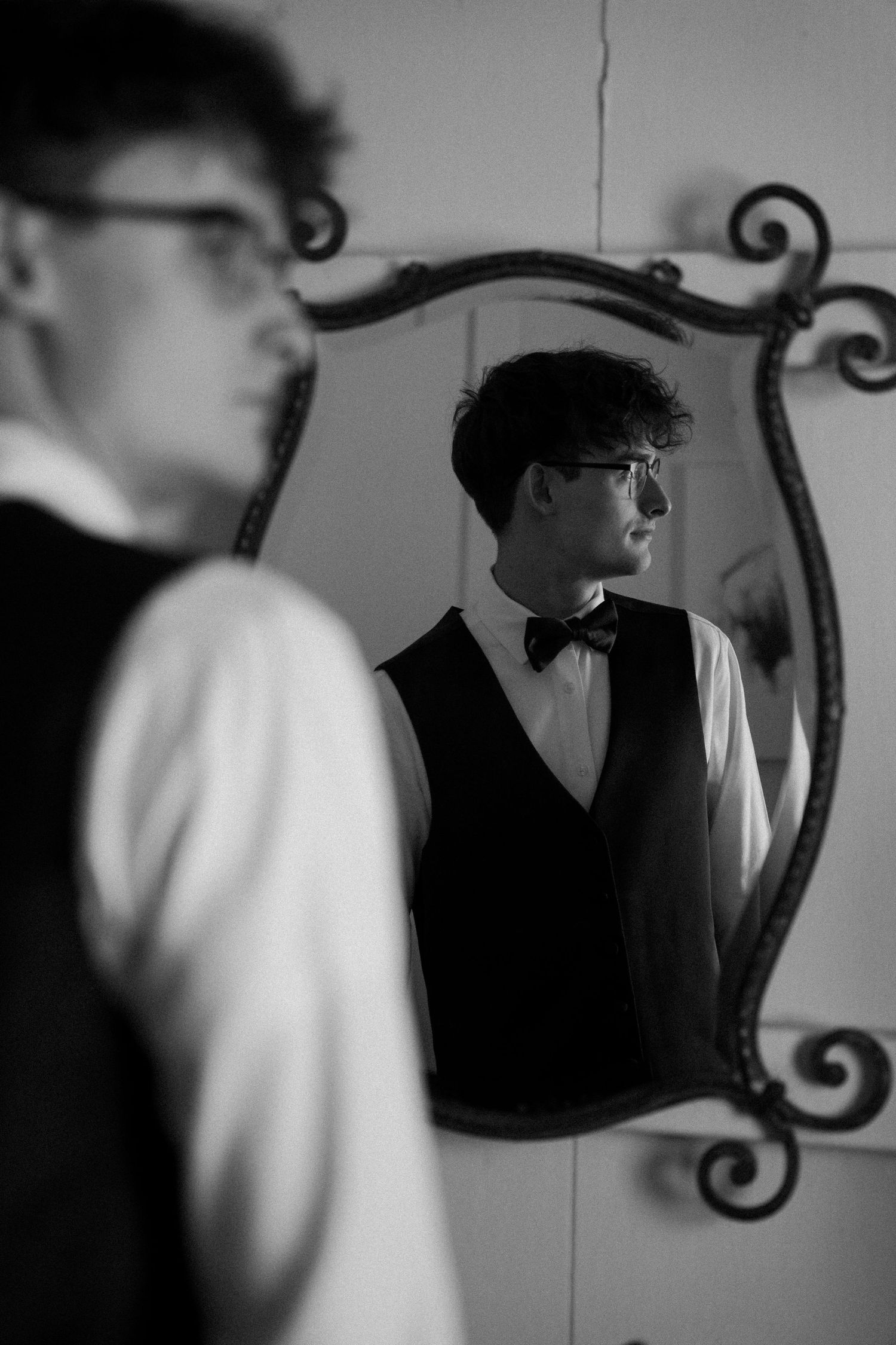 Artistic black and white reflection of someone in an ornate mirror.