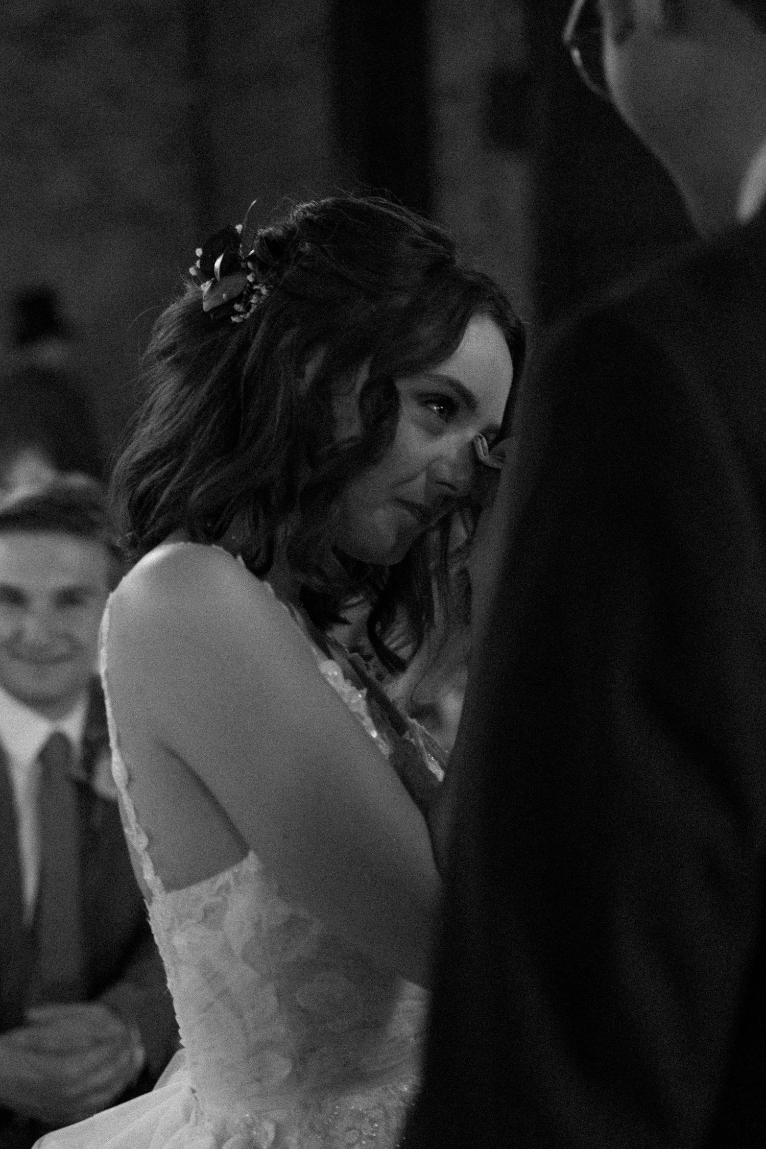 A couple shares a tender dance moment at their wedding reception in dim lighting.