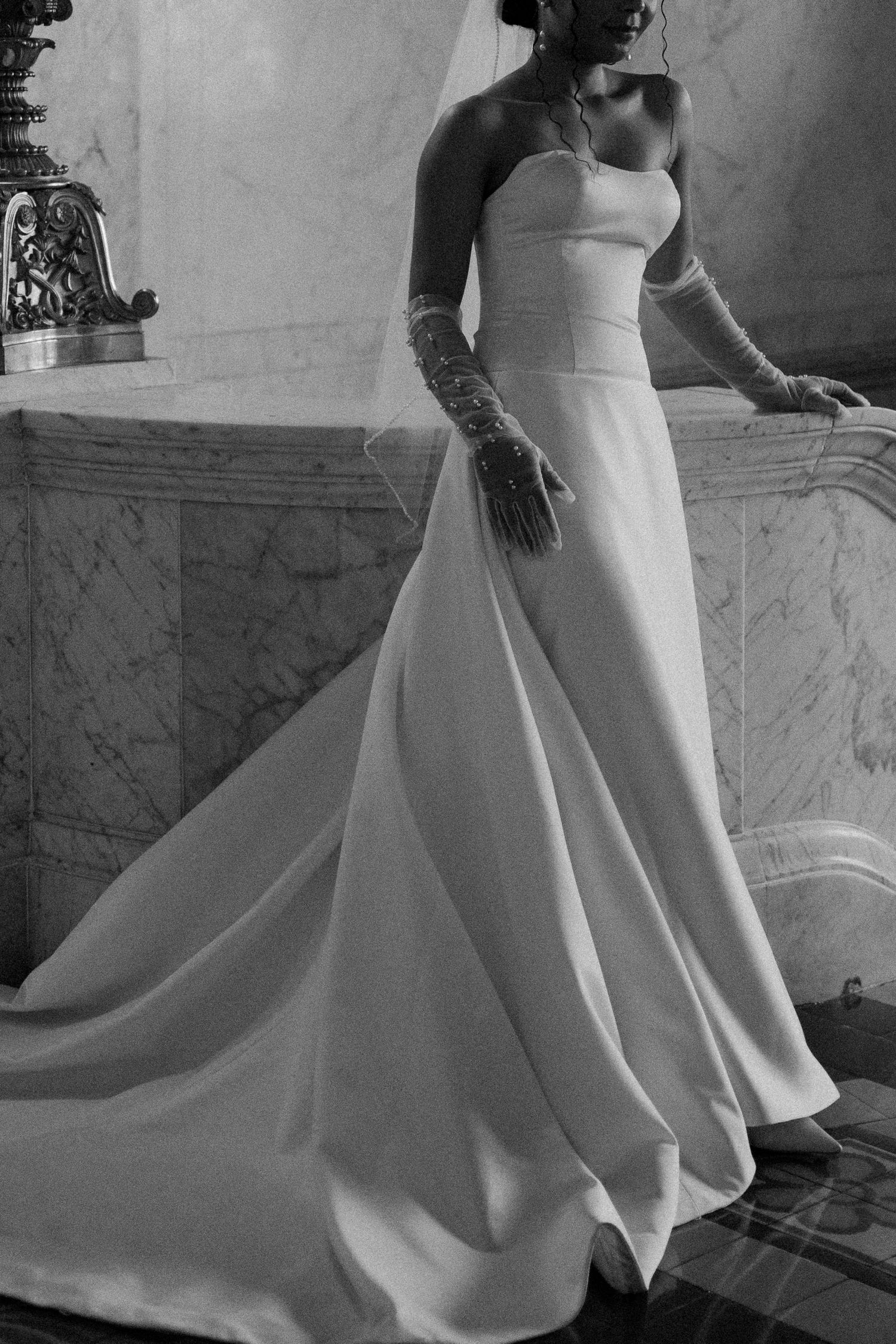 Flowing white wedding dress with dramatic train captured in black and white photography.