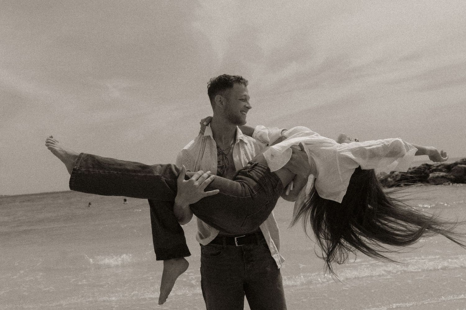 Couple playing on beach in vintage-style black and white photo.