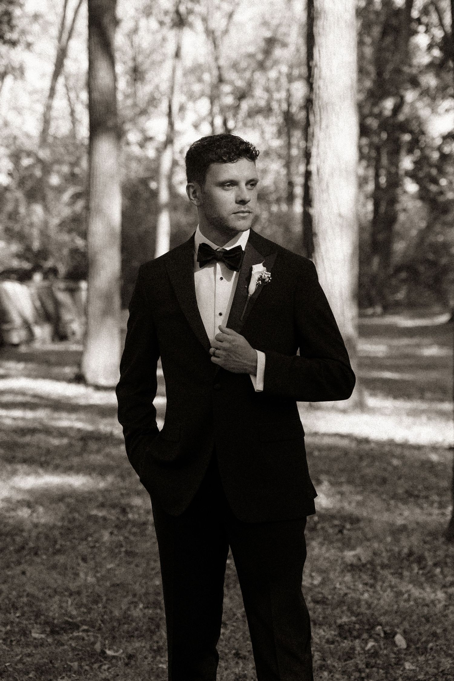 A formal portrait in black and white showing elegant attire in a wooded setting.