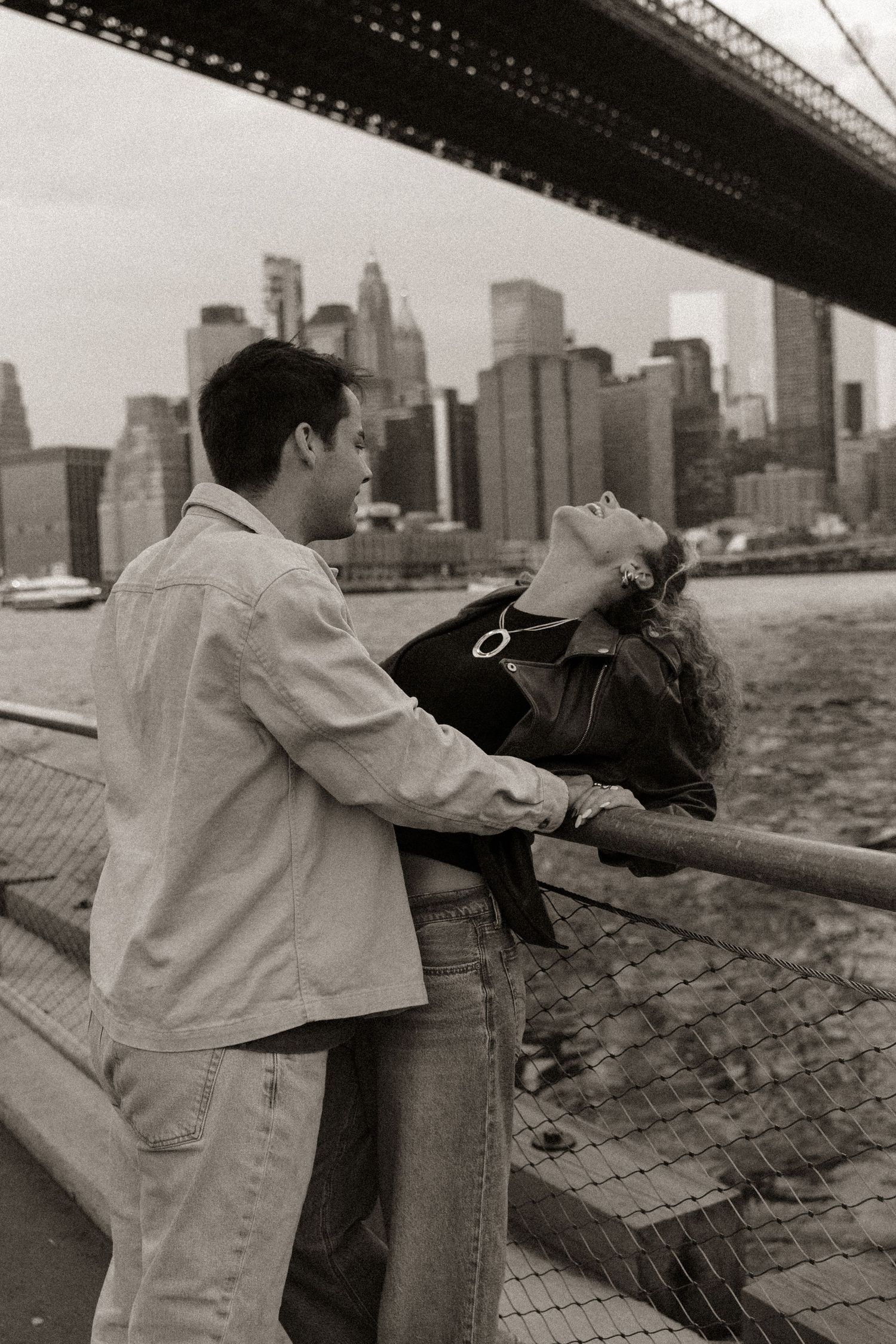A black and white photo series shows two people leaning against a railing with a city skyline in the background.