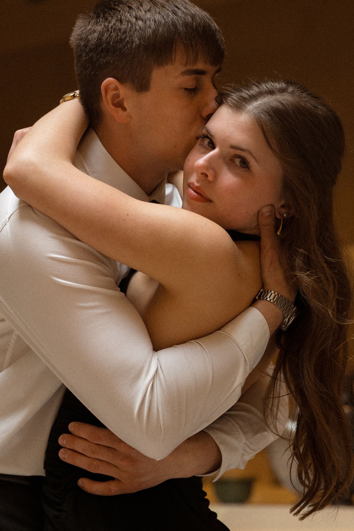 A romantic couple embraces in an intimate dance pose wearing black and white formal attire.