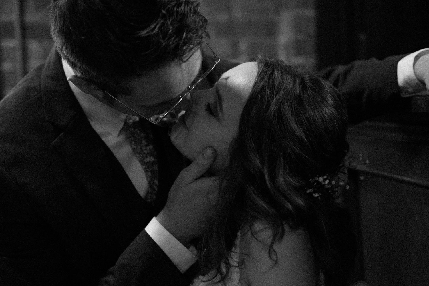 An intimate black and white photo of newlyweds sharing a romantic moment.