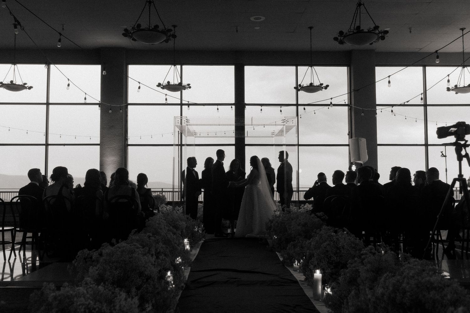 Panoramic silhouette of reception venue with dramatic lighting and large windows.