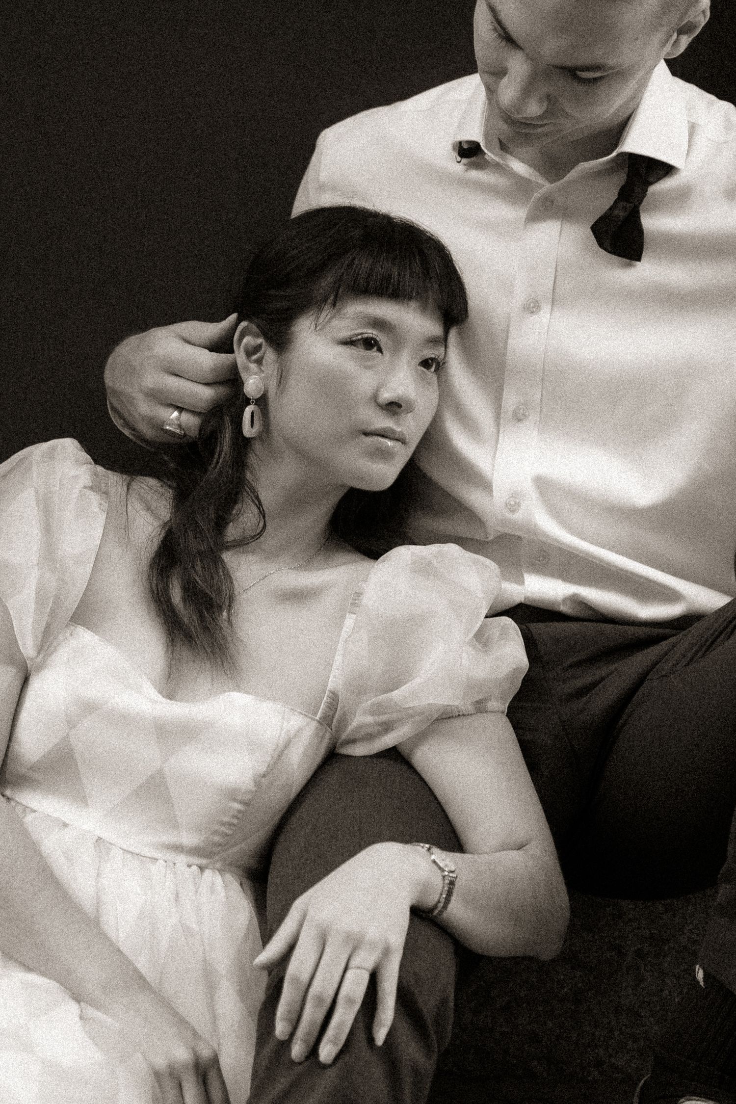 A couple in white attire share intimate moments in black and white photography.