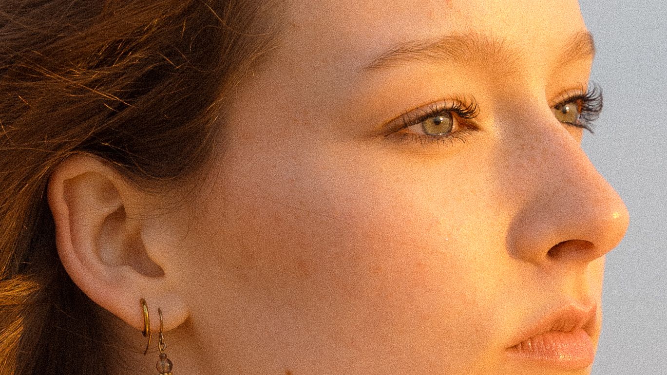 Artistic close-up profile portrait with dramatic side lighting and neutral background.