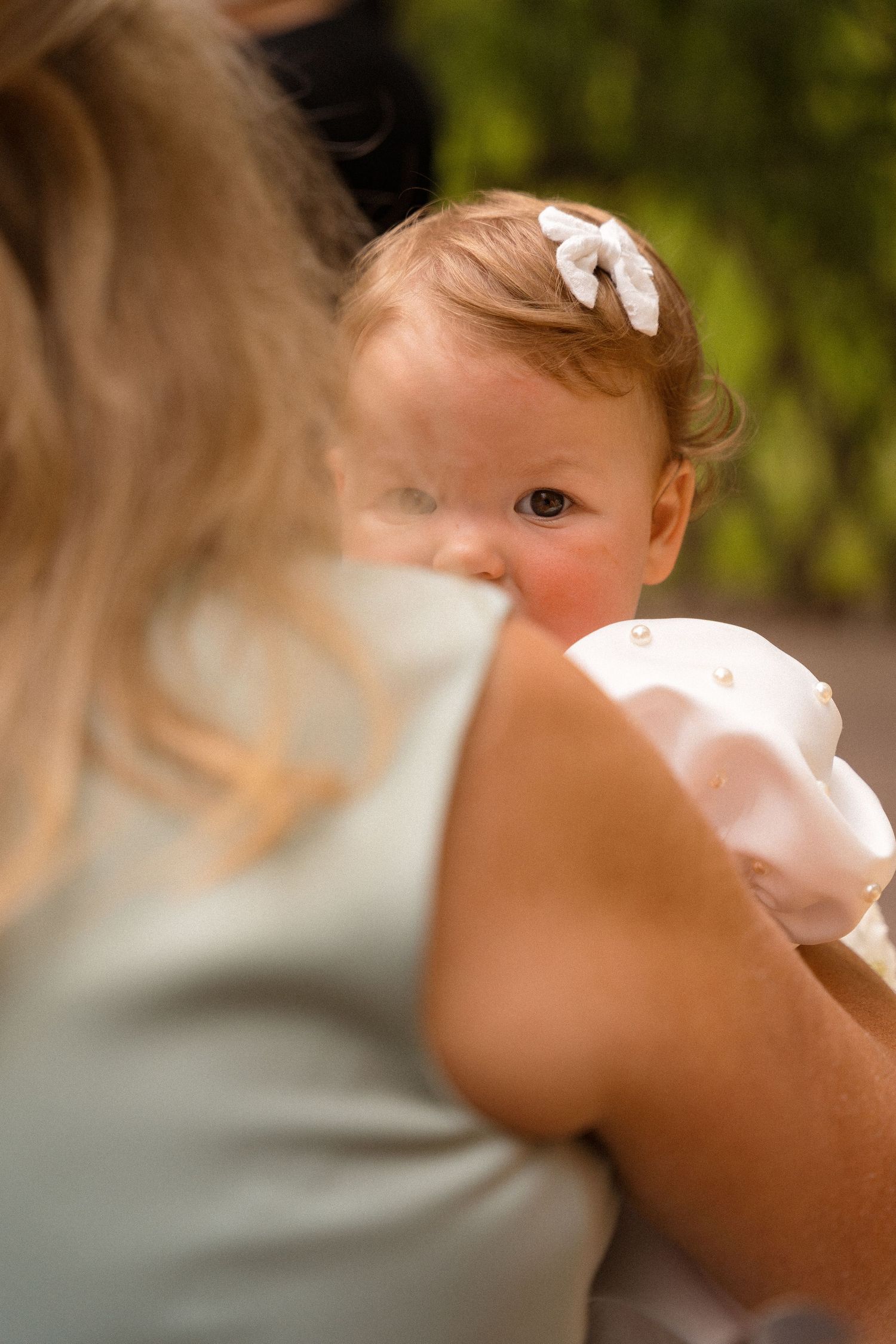 A delicate white bow hair accessory detail photographed in soft focus.