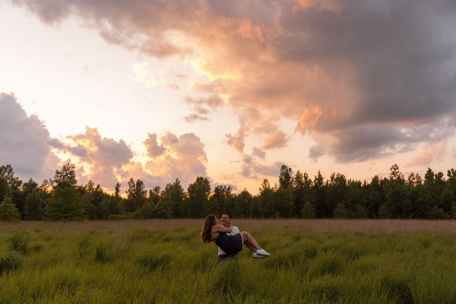 Dramatic sunset sky with orange clouds over a grassy field.