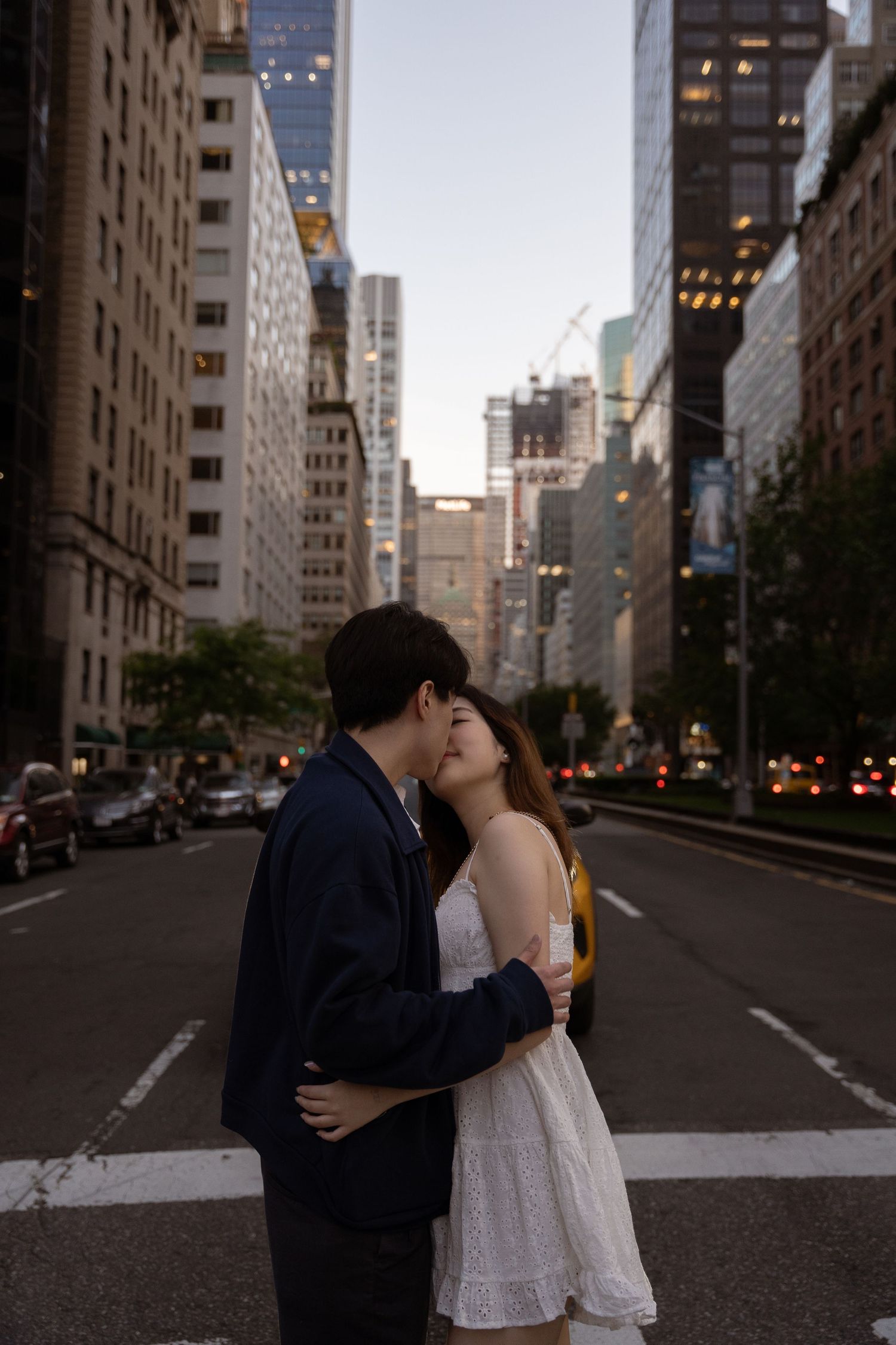 Urban romance scene on empty city street with tall buildings and evening lights.