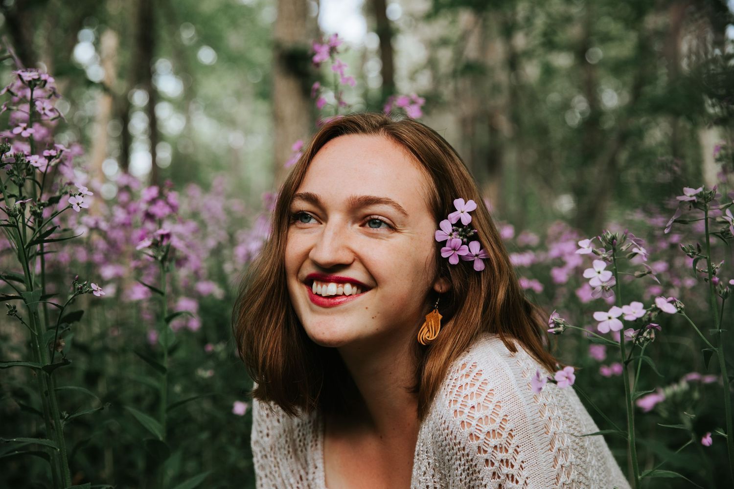 Purple wildflowers frame a joyful outdoor portrait in natural lighting.