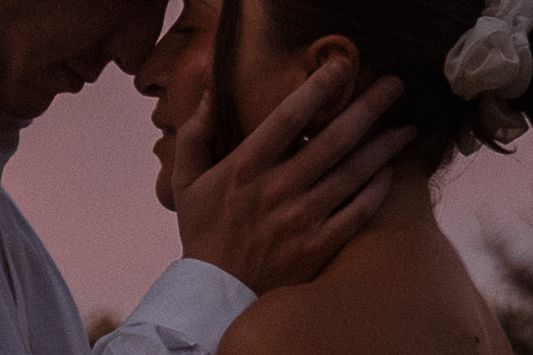Silhouetted romantic moment against pink sunset sky.