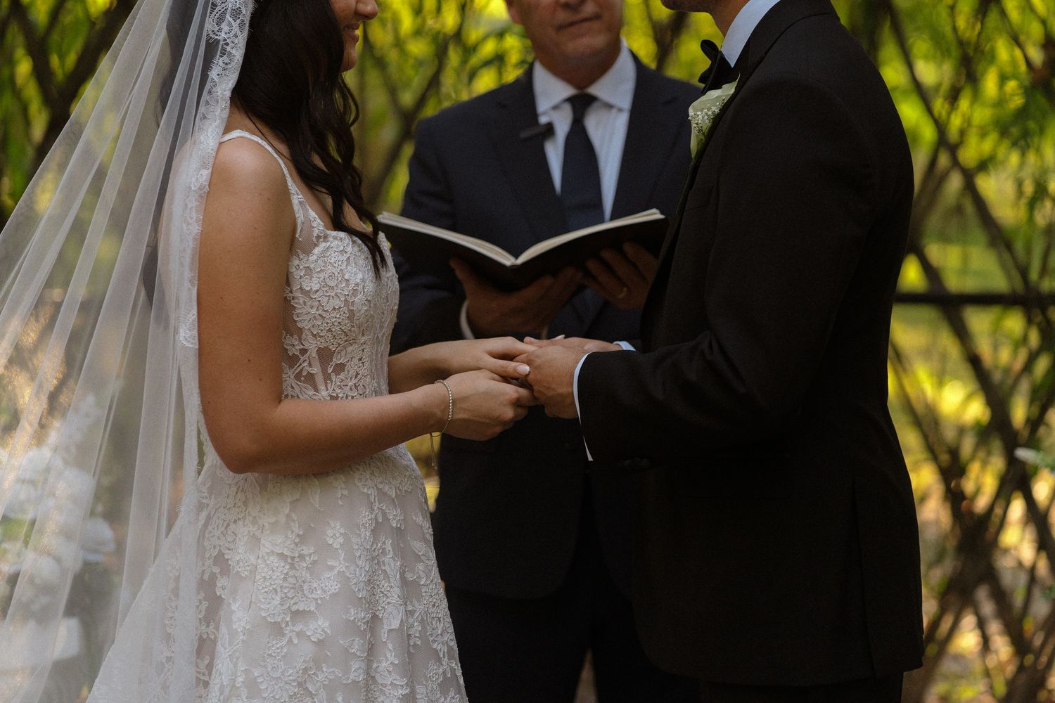 Outdoor wedding ceremony with lush greenery backdrop and formal attire.