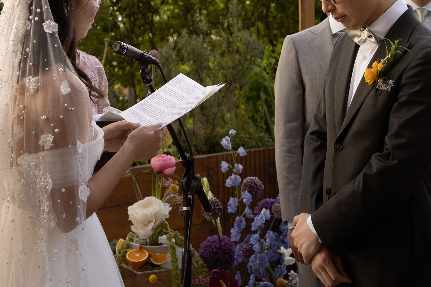 Wedding ceremony outdoors with purple flowers and natural greenery.