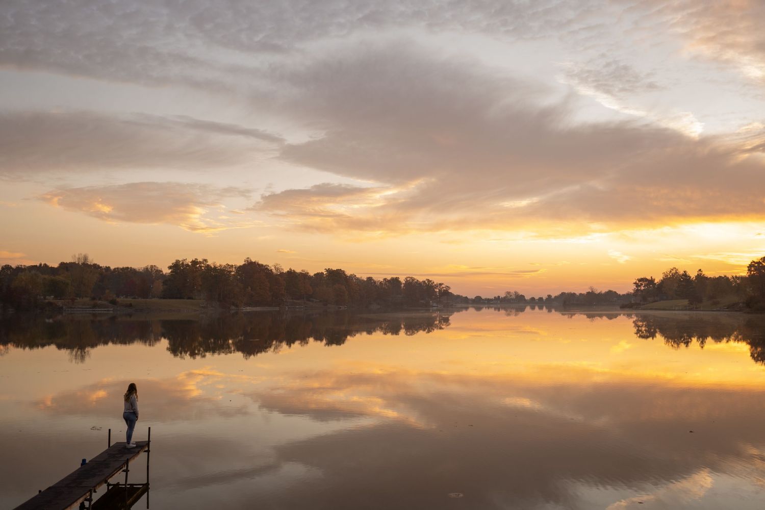 Panoramic sunset landscape over a lake with reflective waters and cloudy sky.
