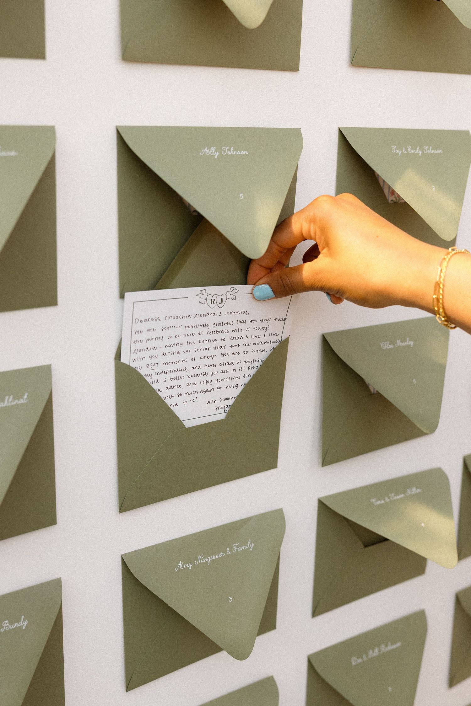 Hand placing handwritten note on wall display with multiple envelopes.