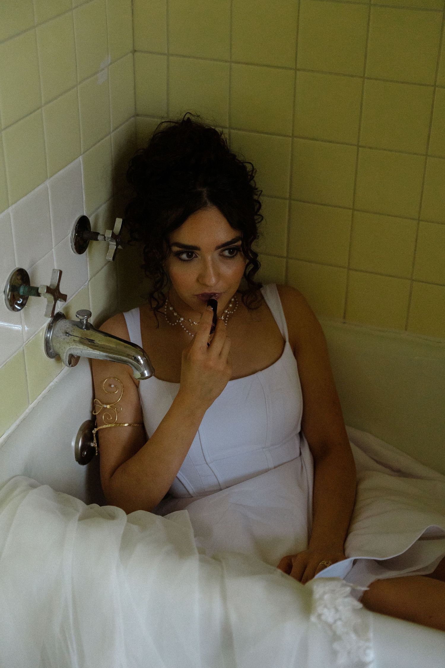 A person in white rests thoughtfully in a bathtub.