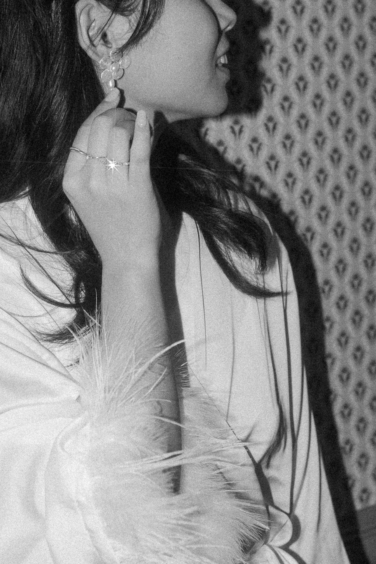 Elegant black and white portrait against vintage wallpaper with delicate feather details.