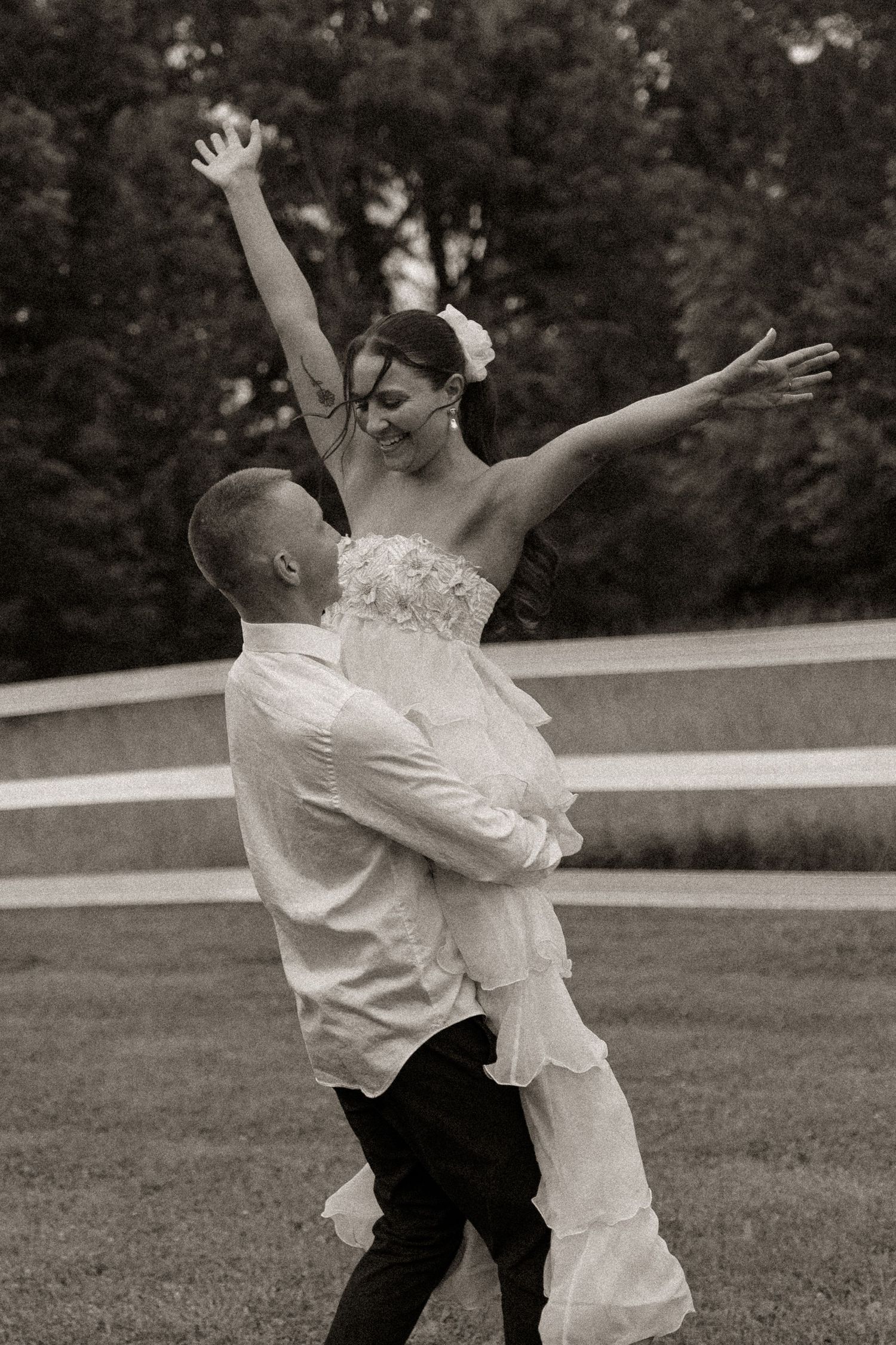 Couple dancing playfully on a grassy lawn during a wedding celebration.