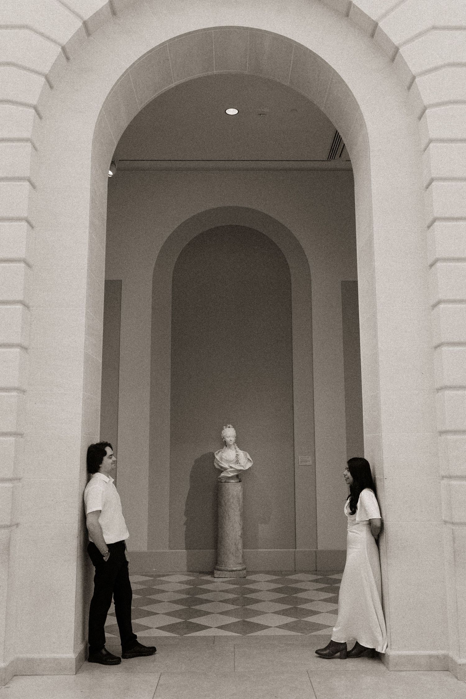 Two figures stand in dramatic arched hallways with black and white checkered floors.