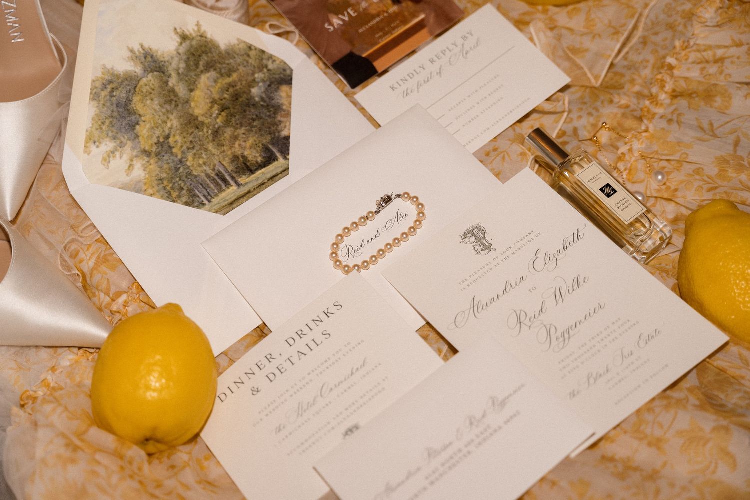 Wedding invitations and citrus fruits arranged on a textured golden surface.