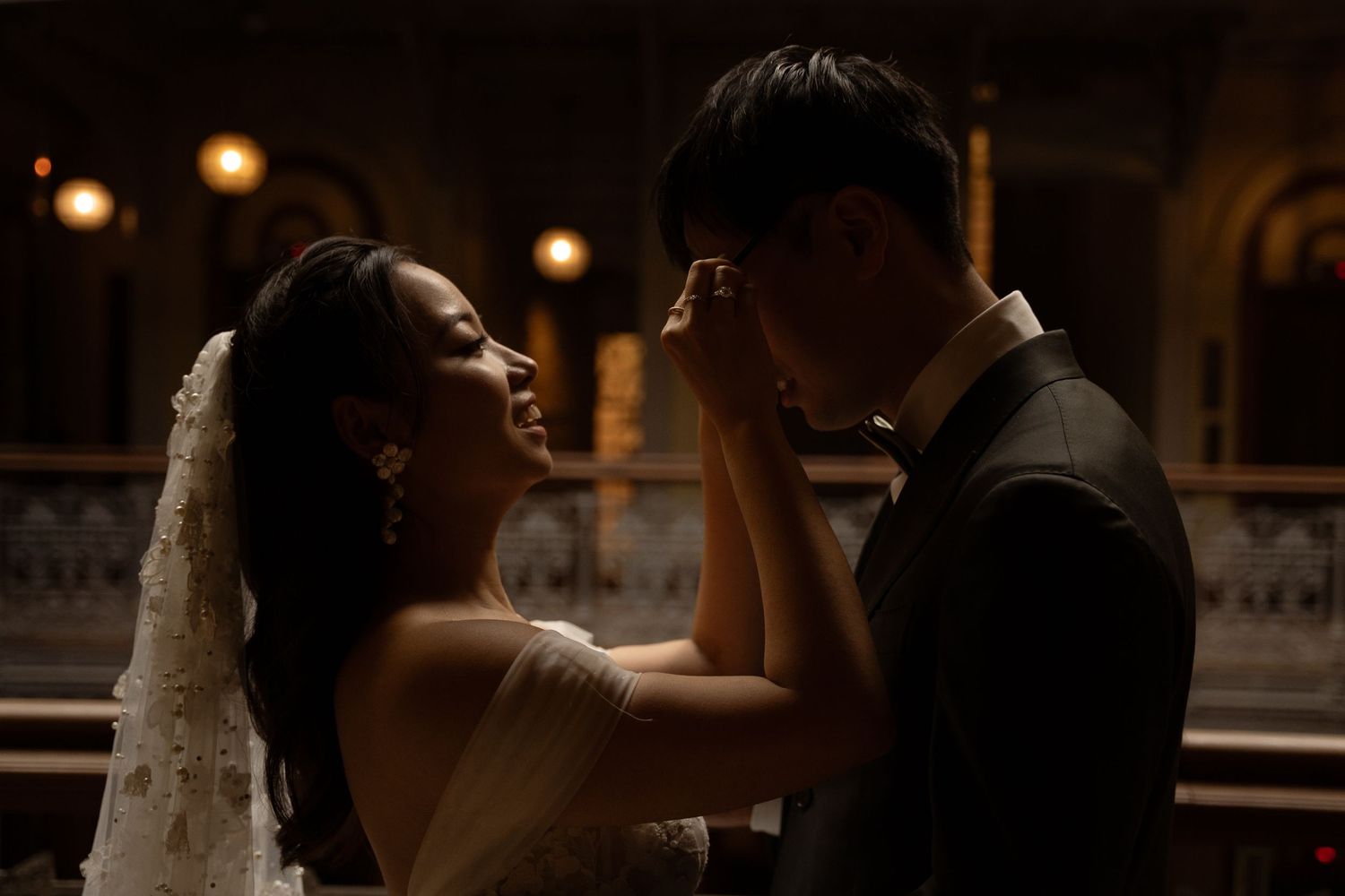 A romantic moment captured between newlyweds in a dimly lit venue with glowing lights.