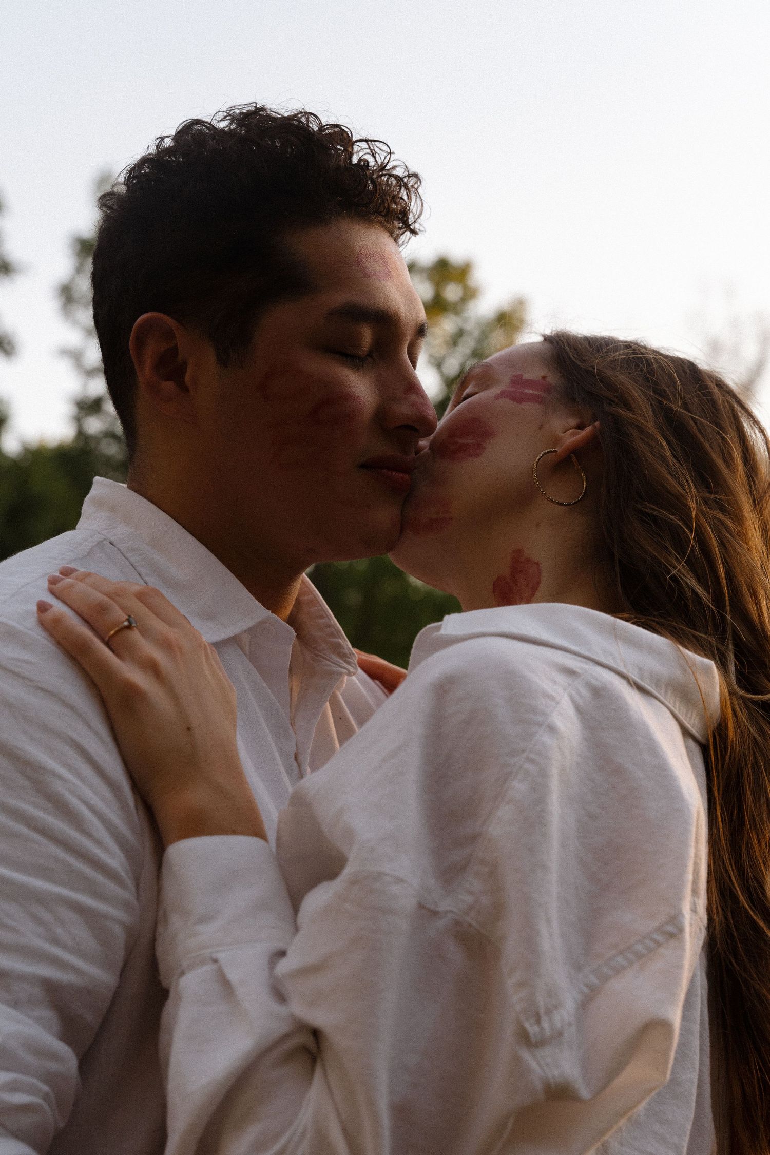 An intimate moment between two people in white shirts during sunset.
