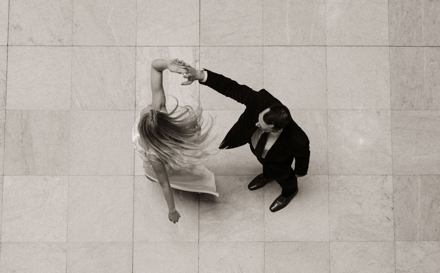 Artistic overhead view of people walking on marble floors in black and white.