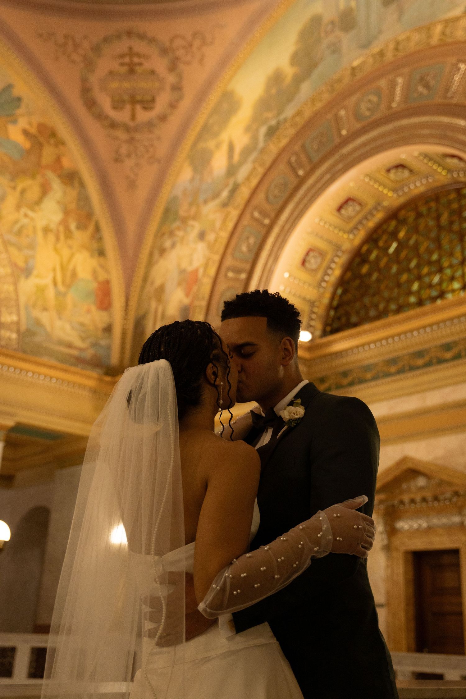 Romantic moment captured under ornate golden cathedral ceiling with beautiful architectural details.