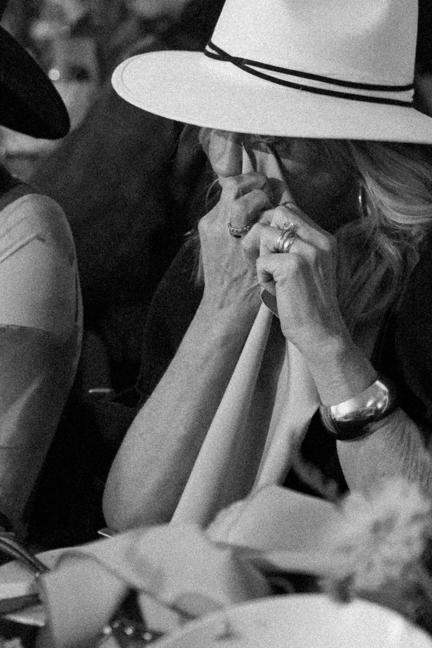 Close-up black and white shot of person in white hat showing engagement ring.