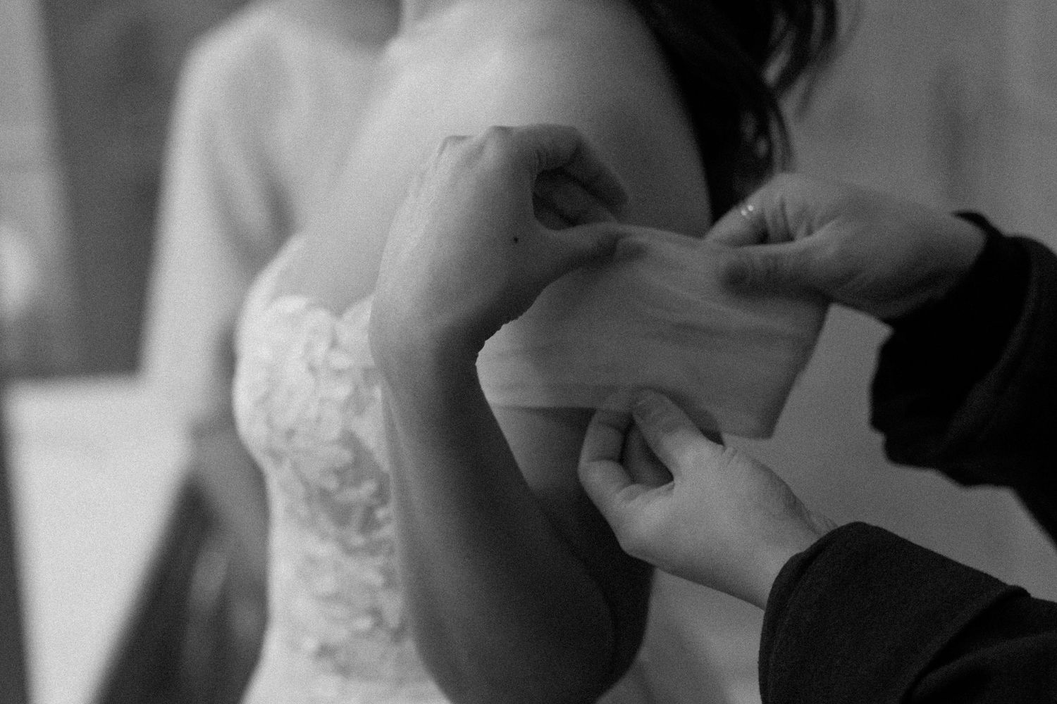 Close-up detail of white lace wedding dress in soft, natural light.