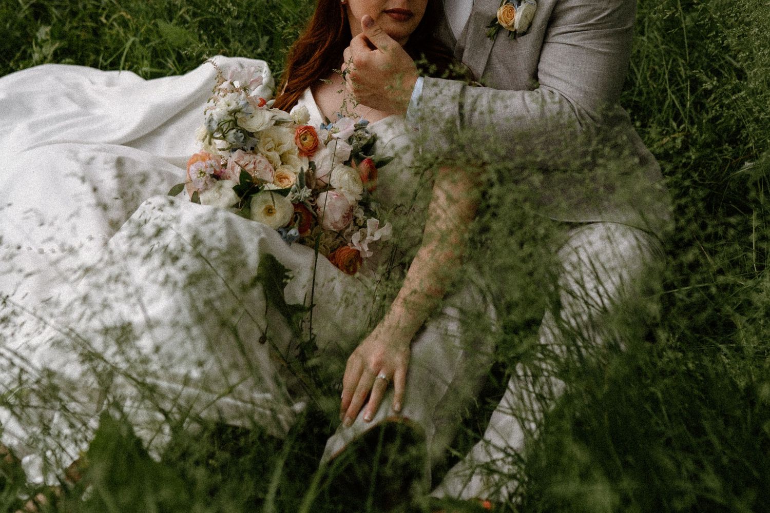 A romantic moment captured in lush green garden setting with white dress details.