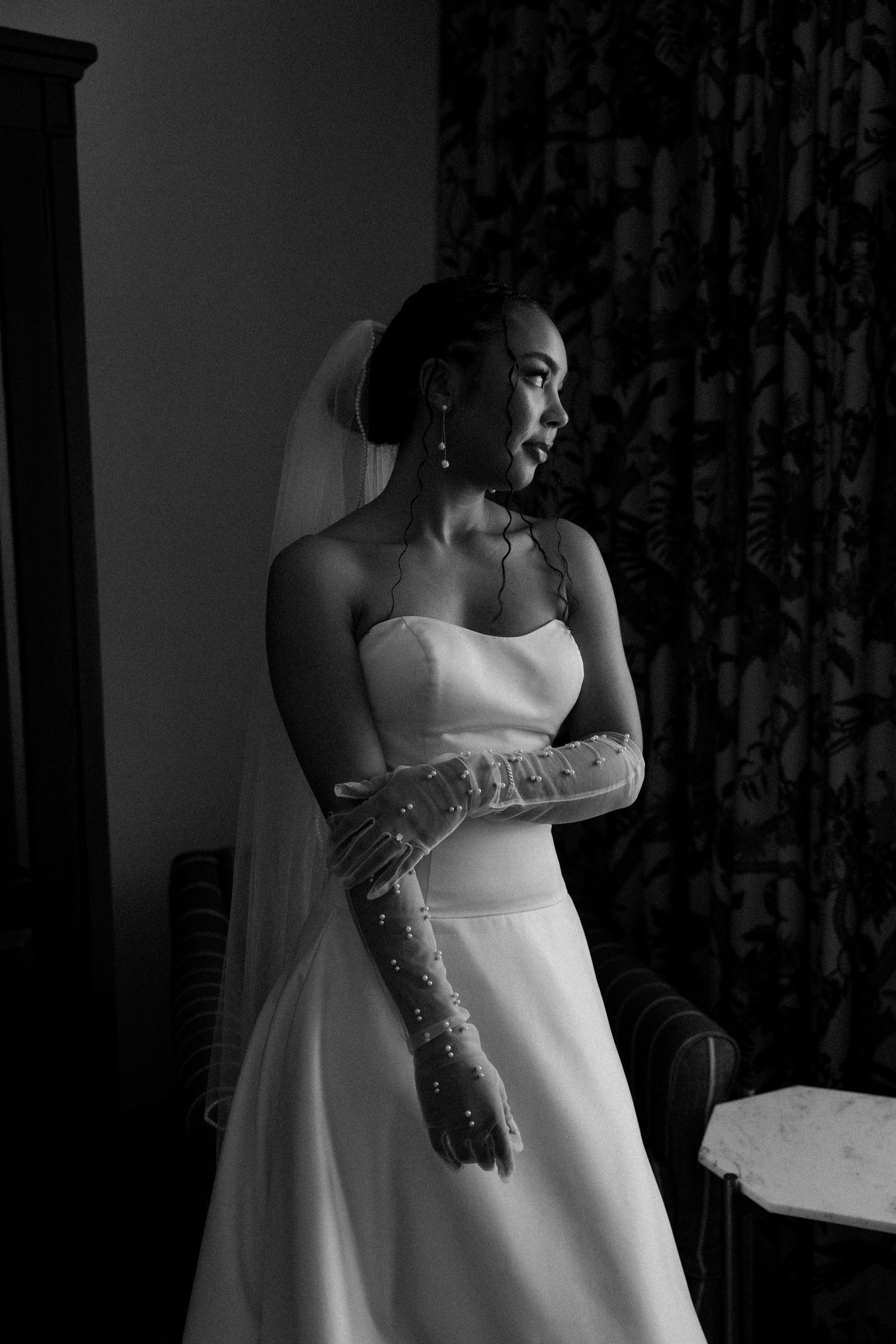 Elegant white wedding dress details shown in dramatic black and white lighting.