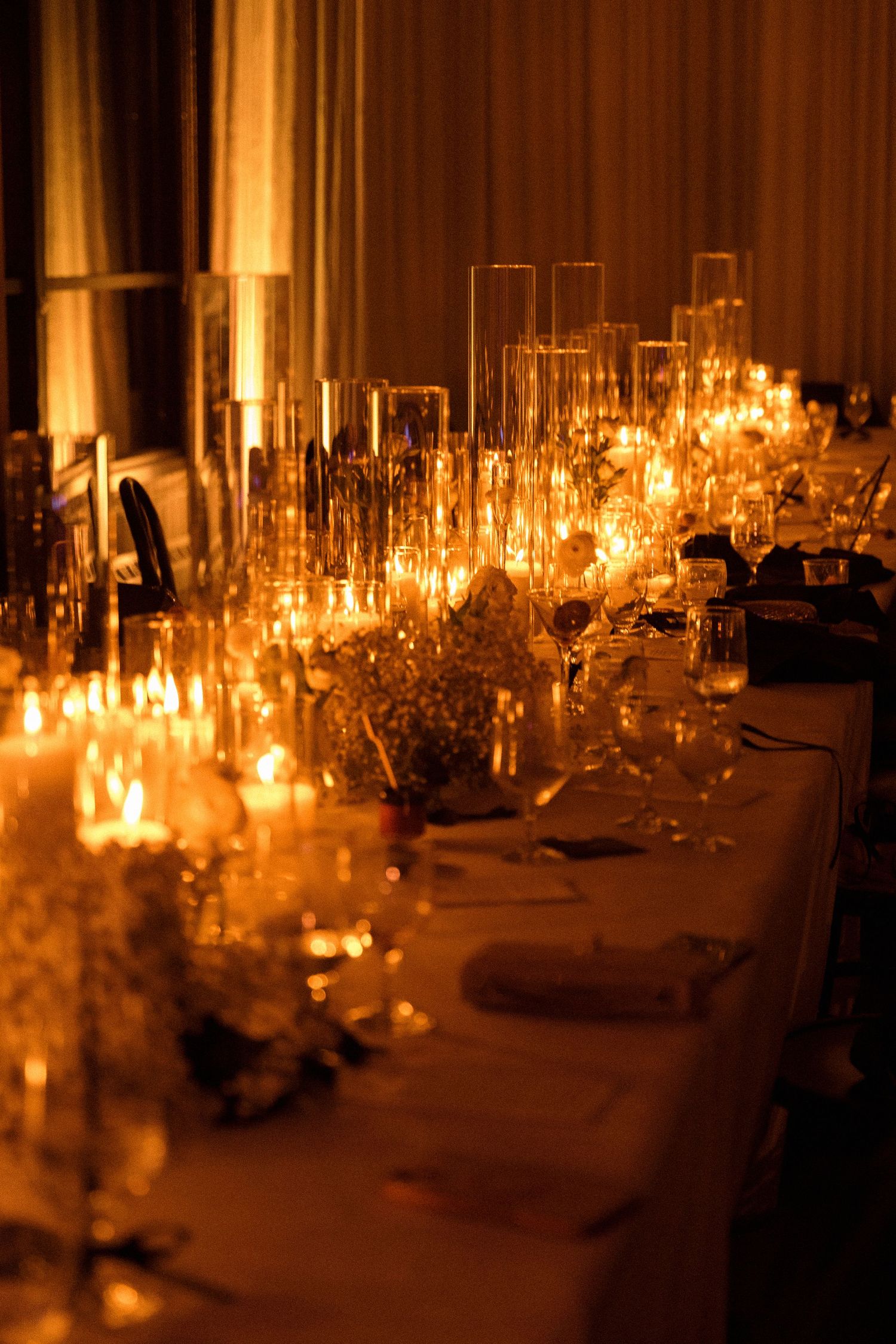Elegant candlelit wedding reception tables with glowing centerpieces.