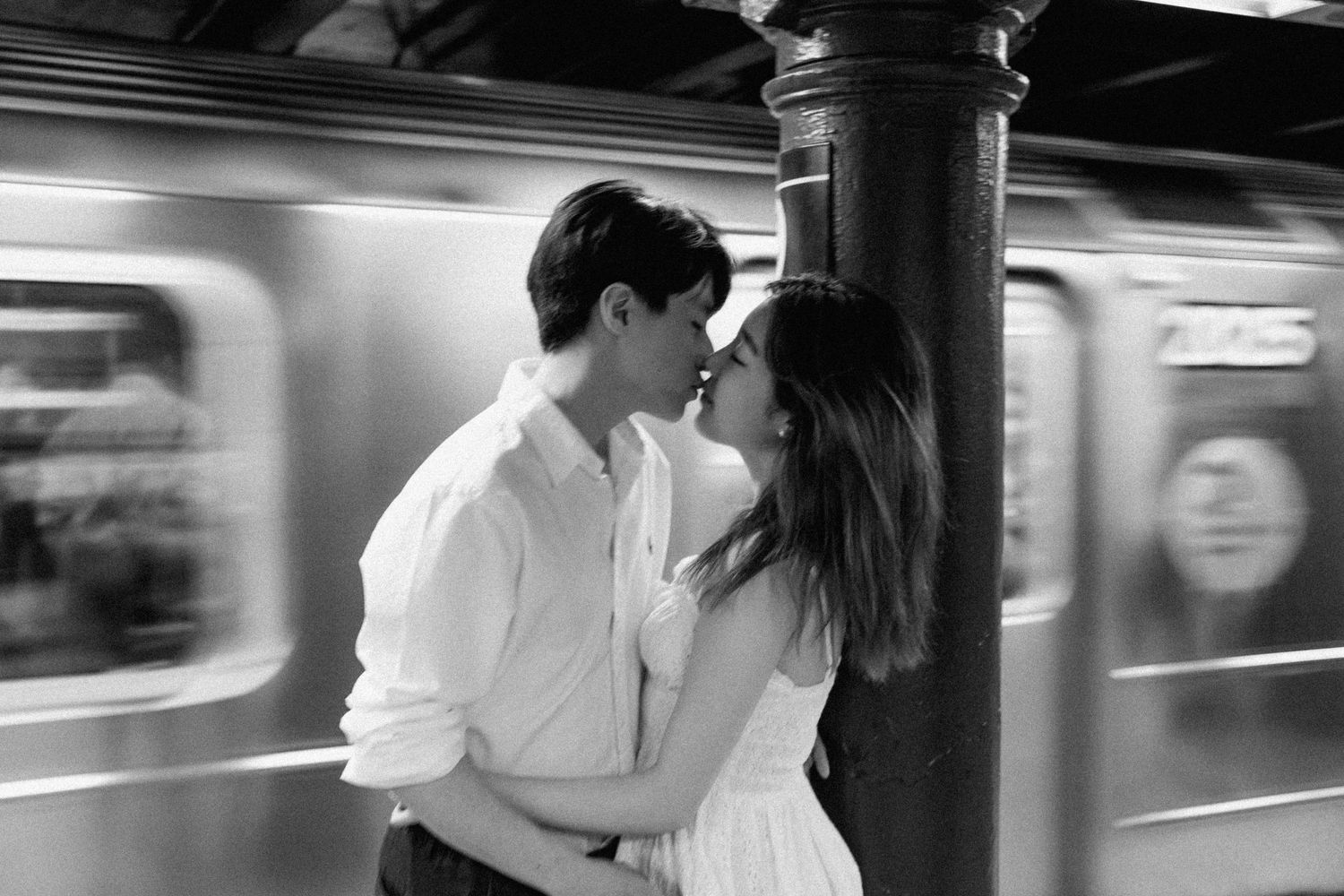 Romantic moment captured in subway station with motion-blurred train in background.