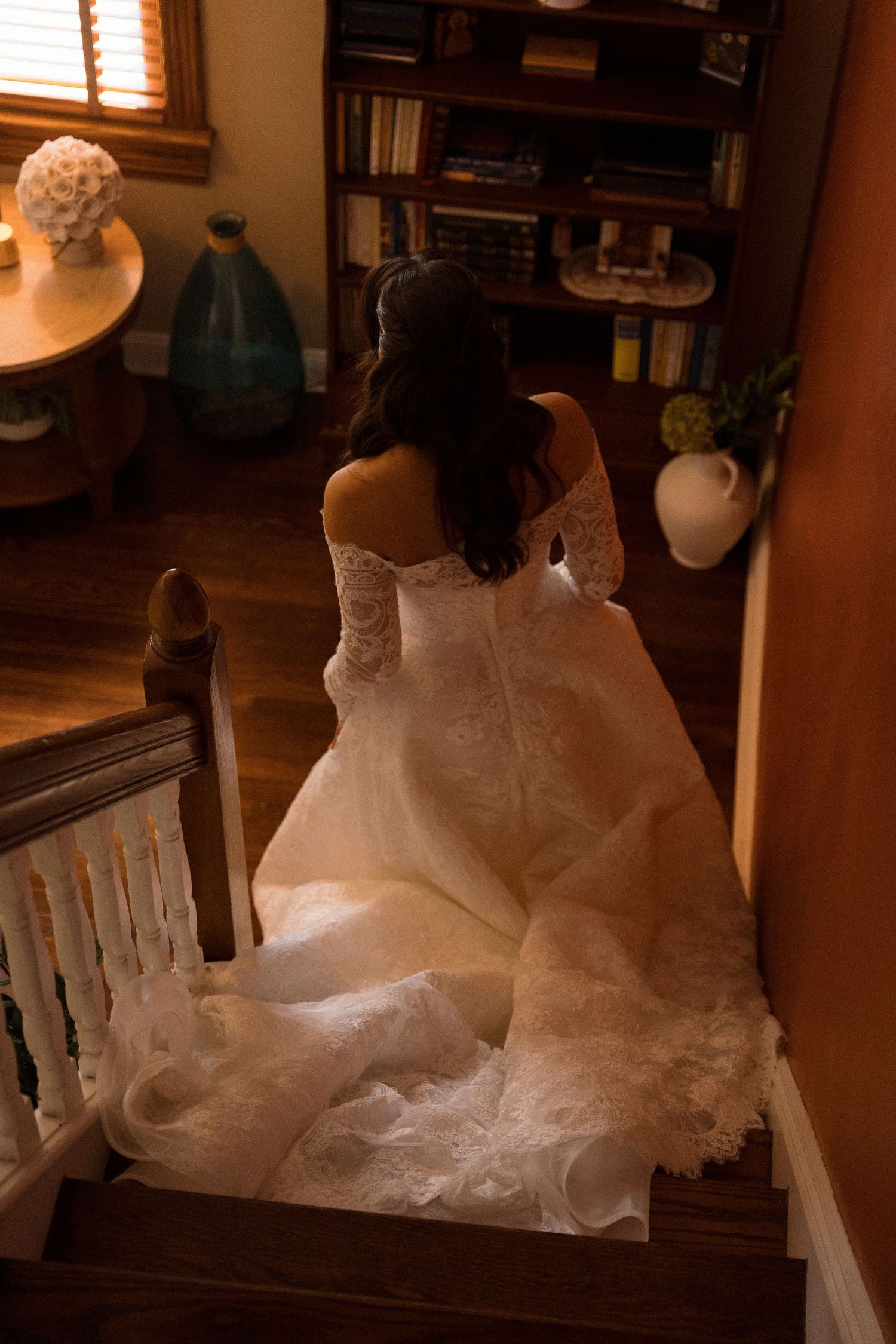 Wedding dress train elegantly arranged on wooden bench in natural lighting.