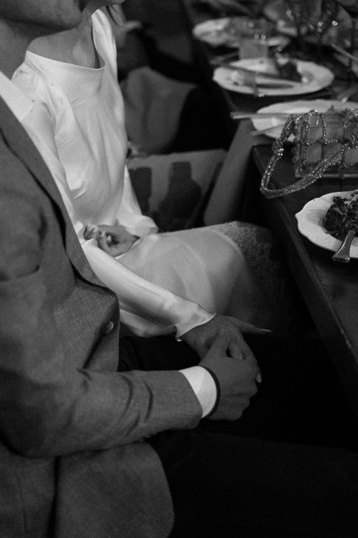 Close-up black and white shot of hands signing documents at a formal event.