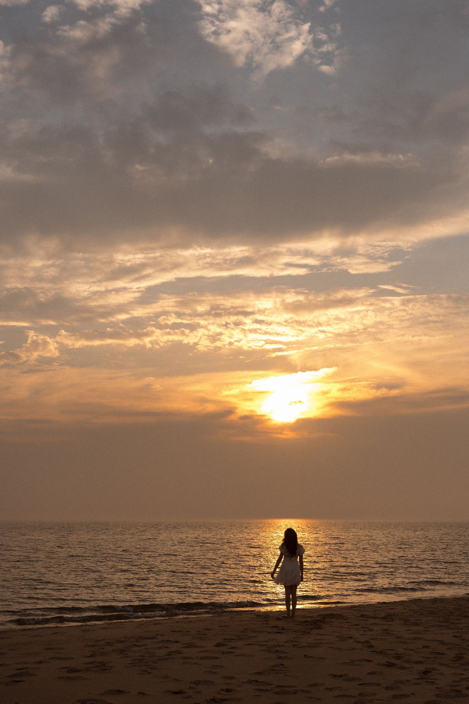 Dramatic beach sunset with silhouetted figures walking along the shoreline.