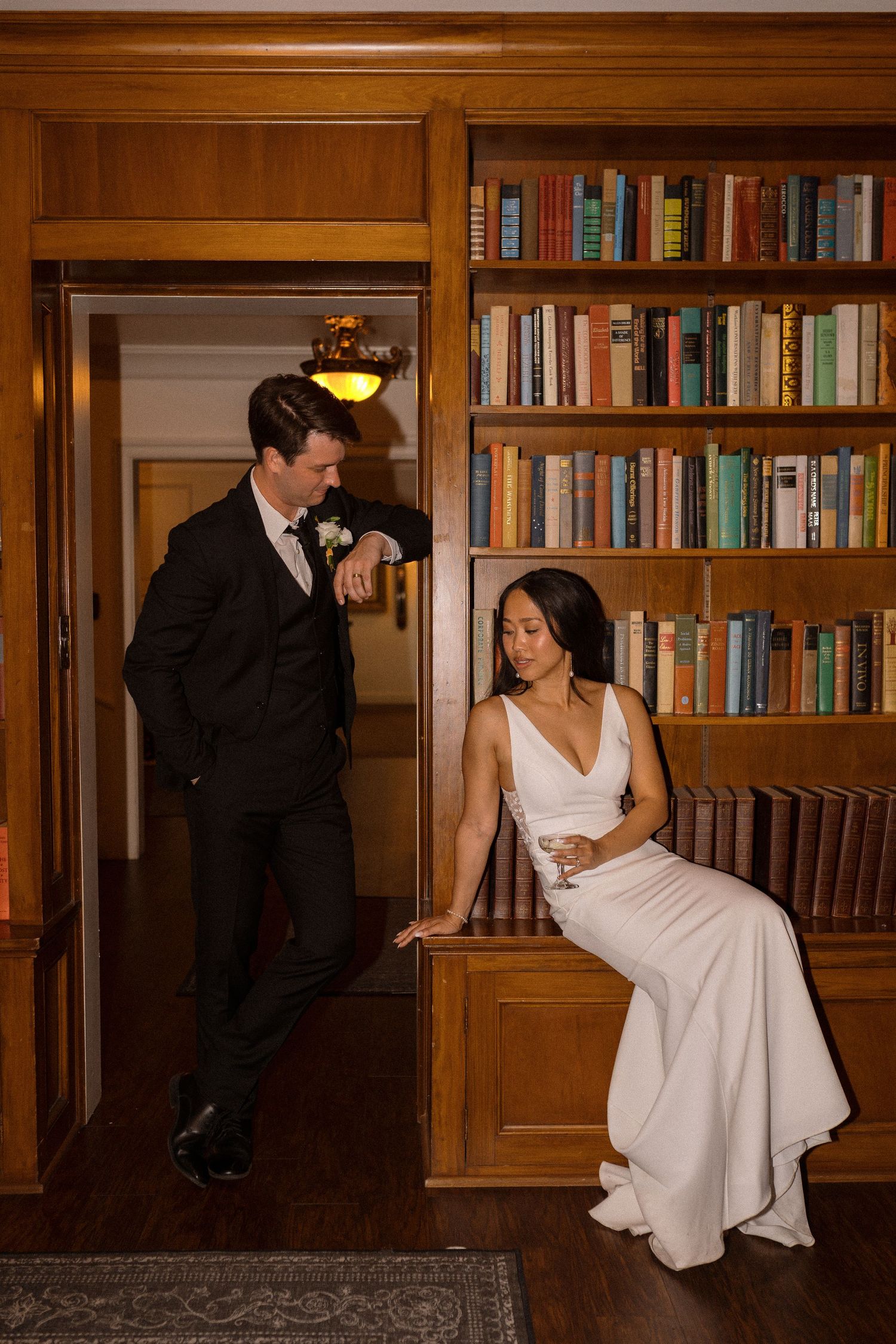 An intimate moment captured in a wood-paneled library with built-in bookshelves.