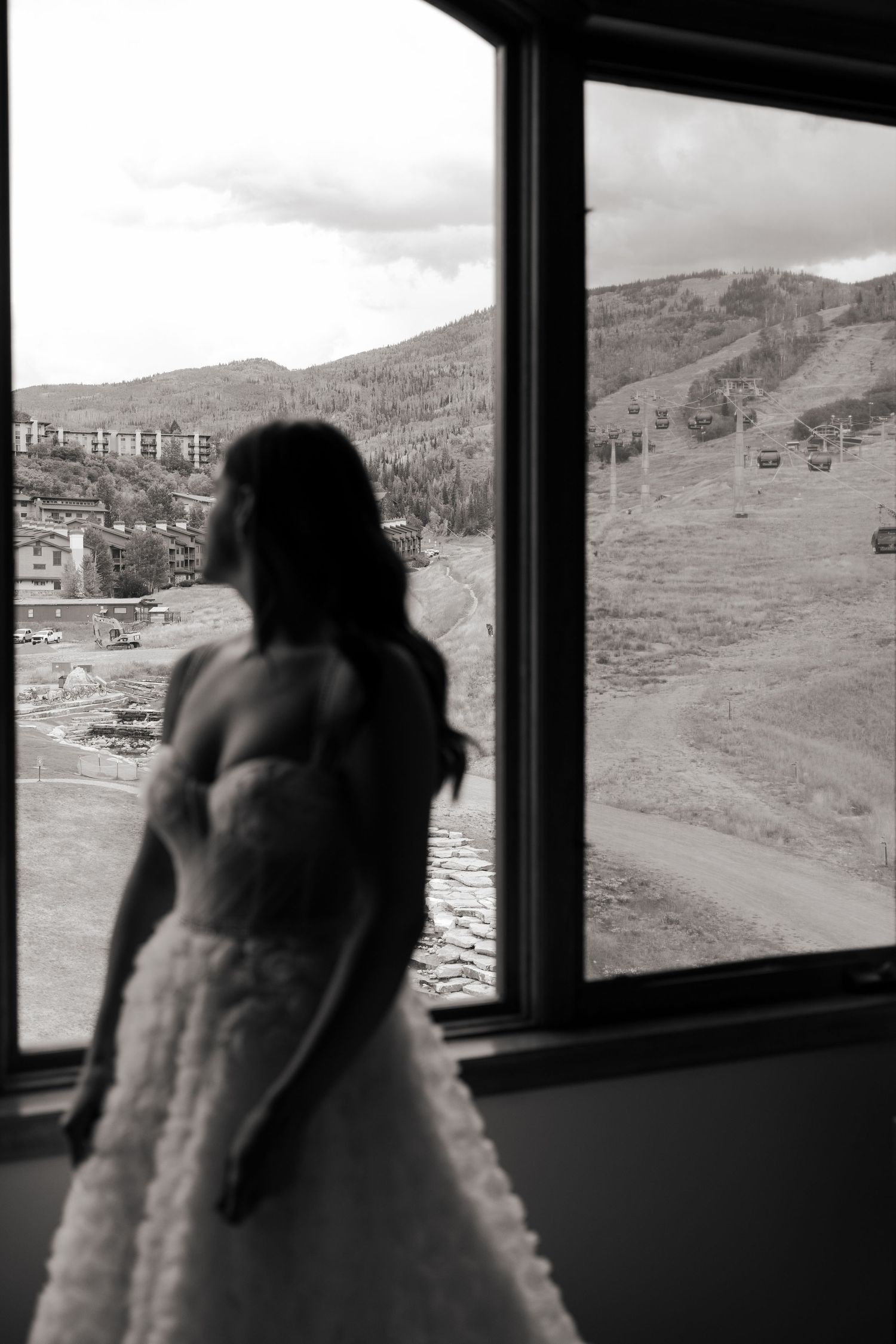 Silhouettes against large windows overlooking mountain landscape at sunset.