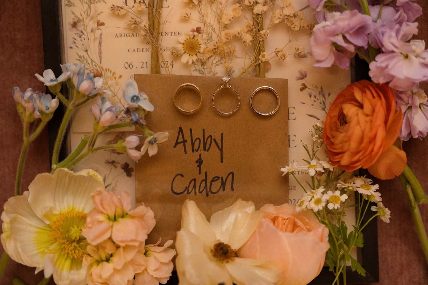 Wedding place cards displayed among pink and orange floral arrangements.