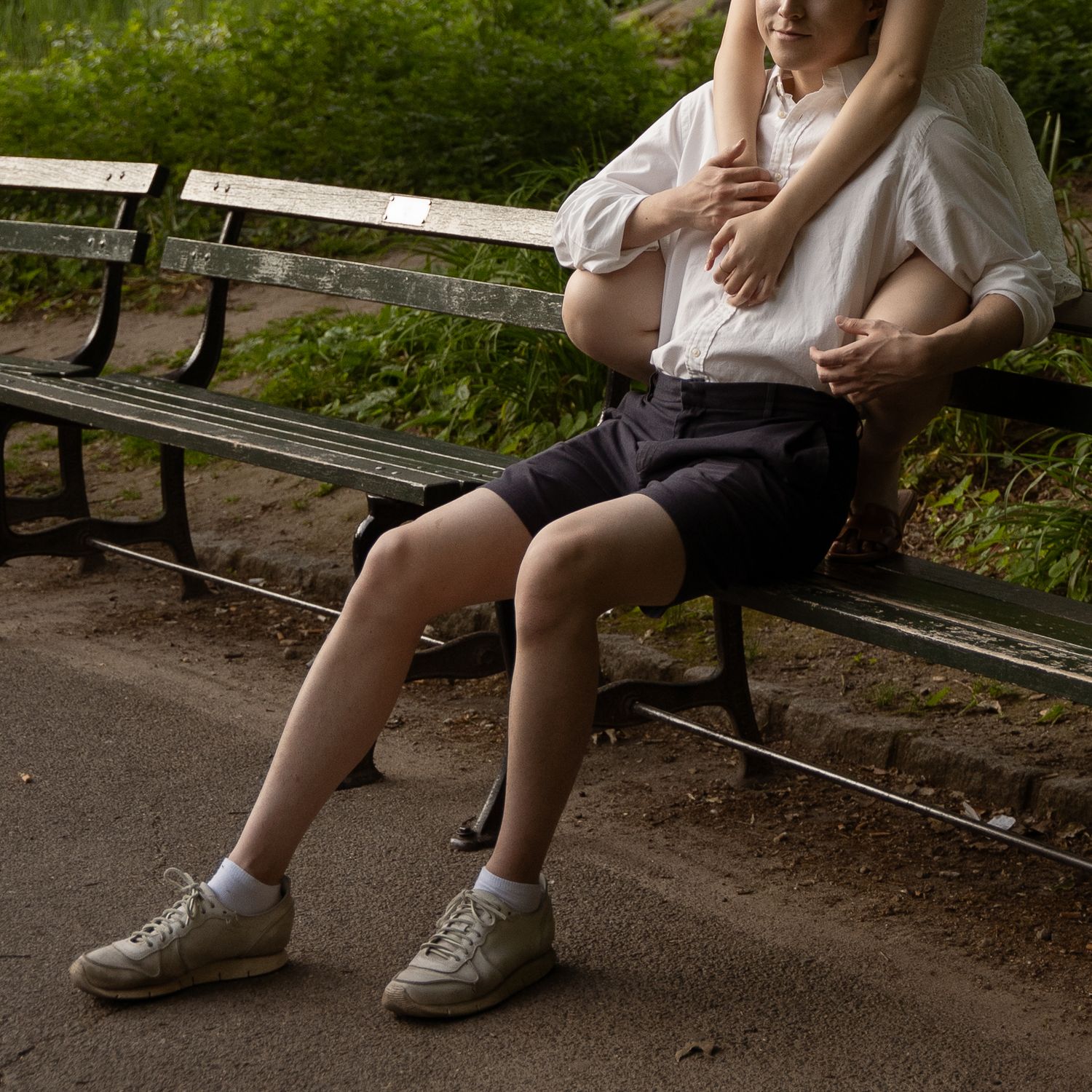Couple sitting together on a park bench surrounded by greenery and flowers.
