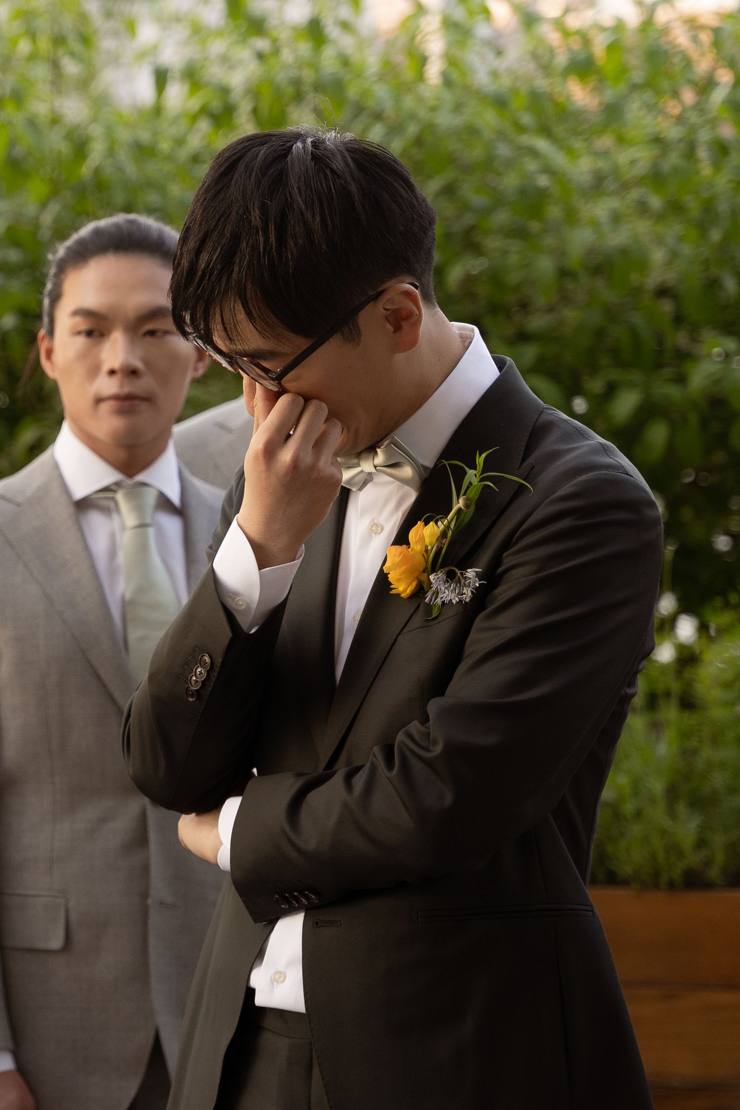 Emotional wedding moment with groomsmen in suits and yellow boutonnieres.