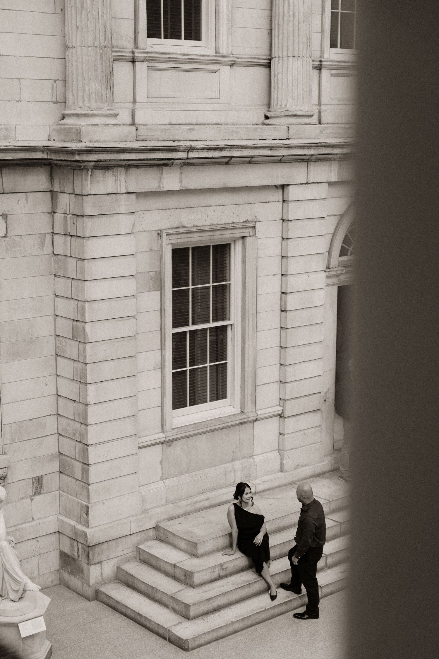 Black and white photograph of figures walking near a grand stone building entrance.