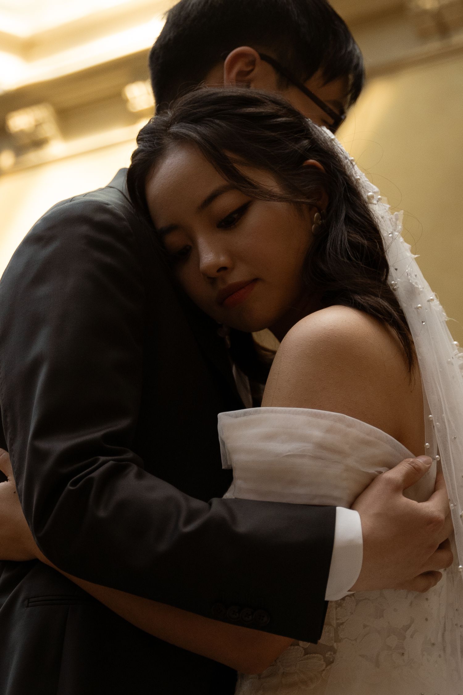 Tender embrace between newlyweds with the bride in a white dress and veil.