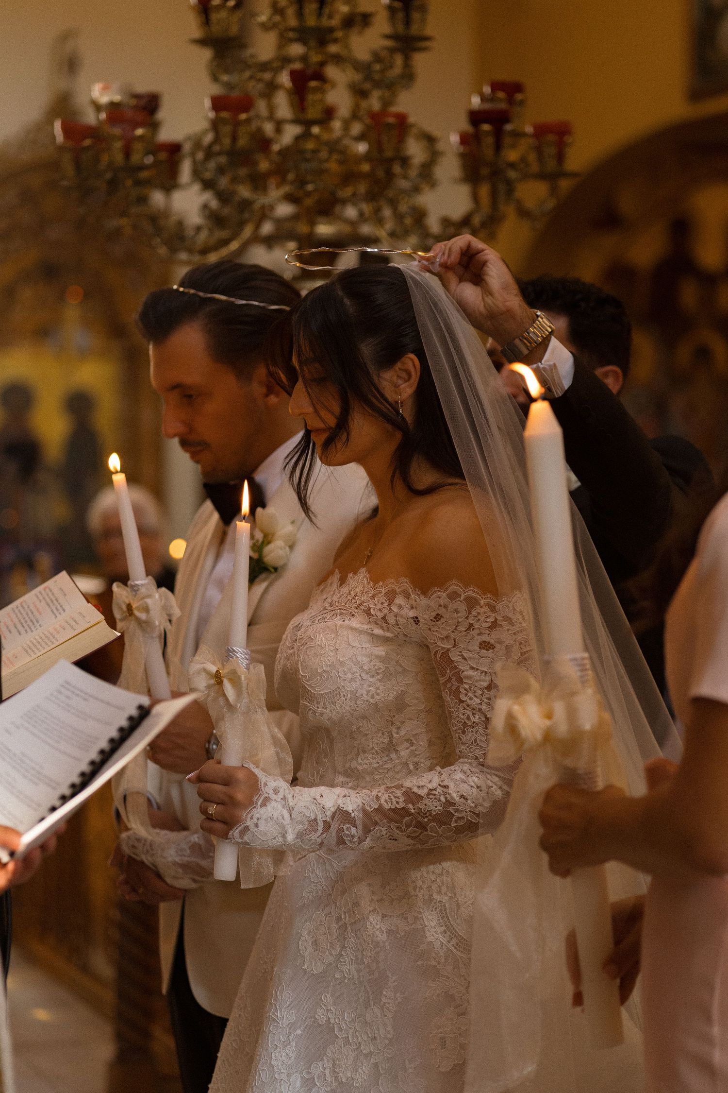 Wedding ceremony participants hold candles during intimate candlelit service.